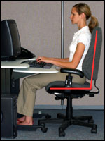A person demonstrating correct neutral seated posture at a computer workstation
