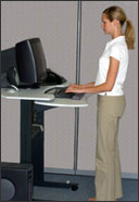 A person demonstrating correct neutral standing posture at a raised workstation